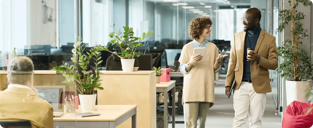 Two colleagues walking and talking in a bright office corridor